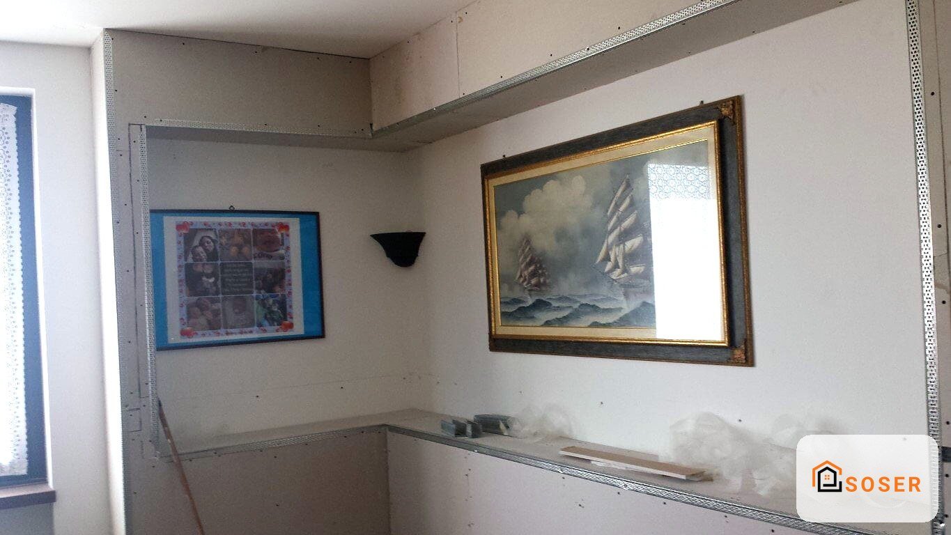 Interno in fase di ristrutturazione con pareti in cartongesso, cornici dorate e quadri appesi