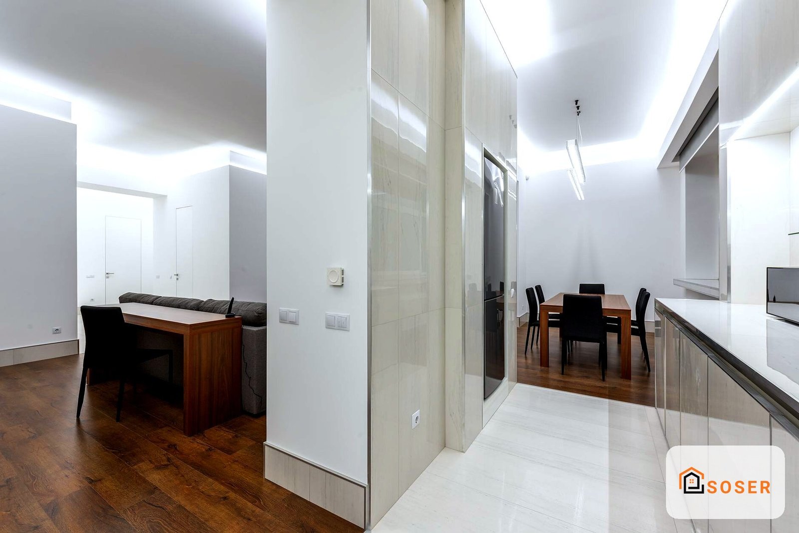 Appartamento moderno ristrutturato con cucina bianca, sala da pranzo e zona living, pavimenti in legno scuro e soffitto con illuminazione a LED
