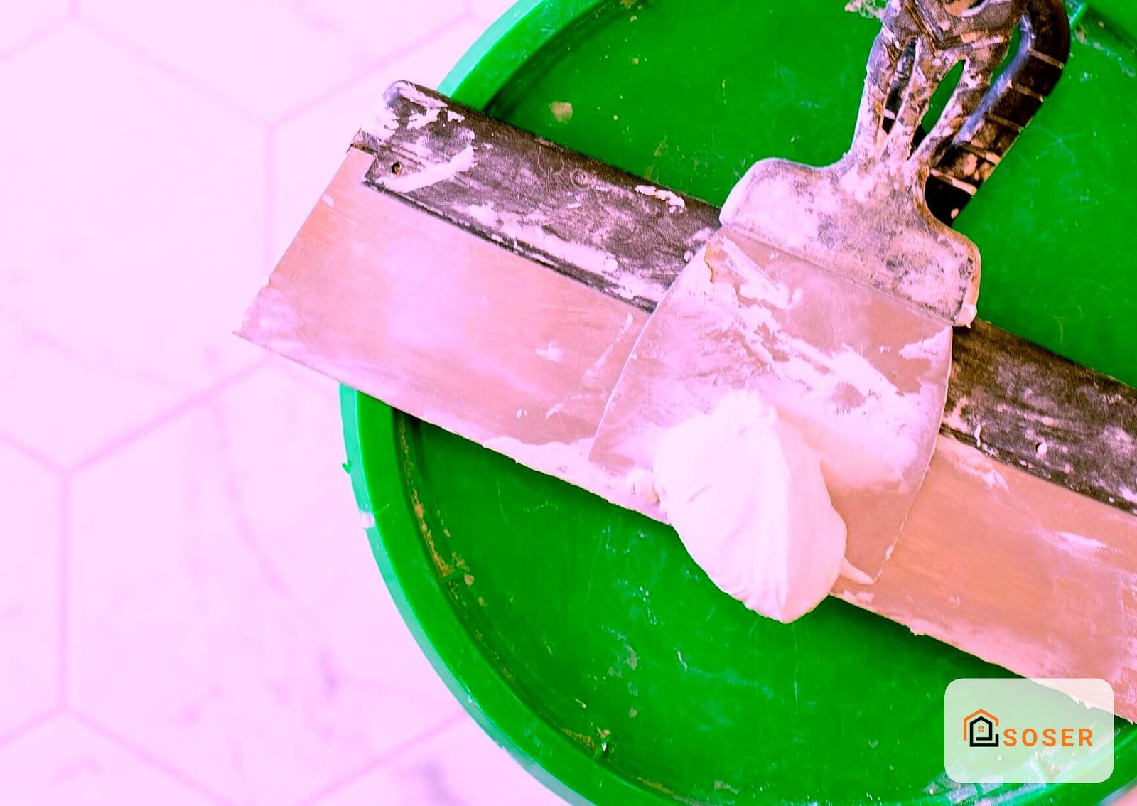 Pennello con pittura rosa su secchio verde per lavori di imbiancatura e pittura