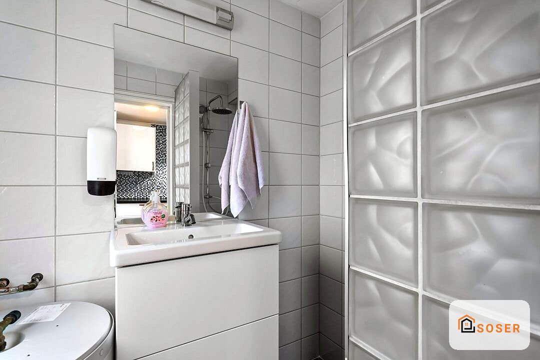 Bagno moderno con piastrelle bianche, lavabo sospeso bianco, specchio illuminato e box doccia con vetri decorativi