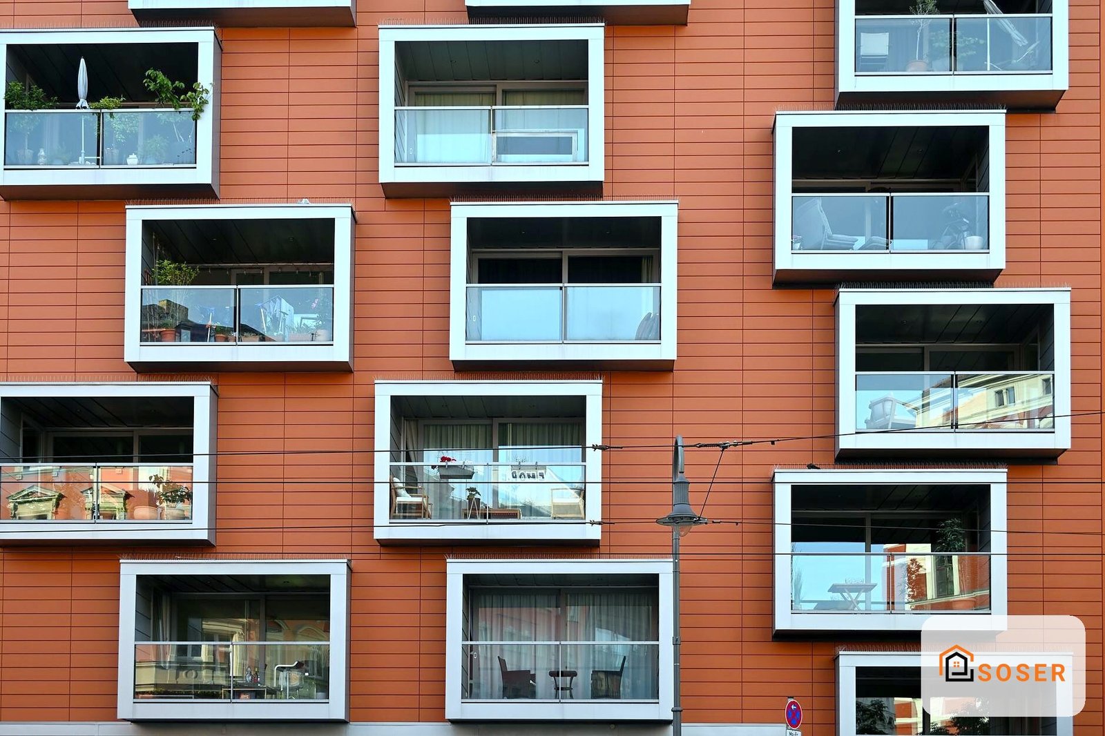 Facciata moderna in laterizio rosso-arancio con finestre in alluminio bianco e balconate in vetro