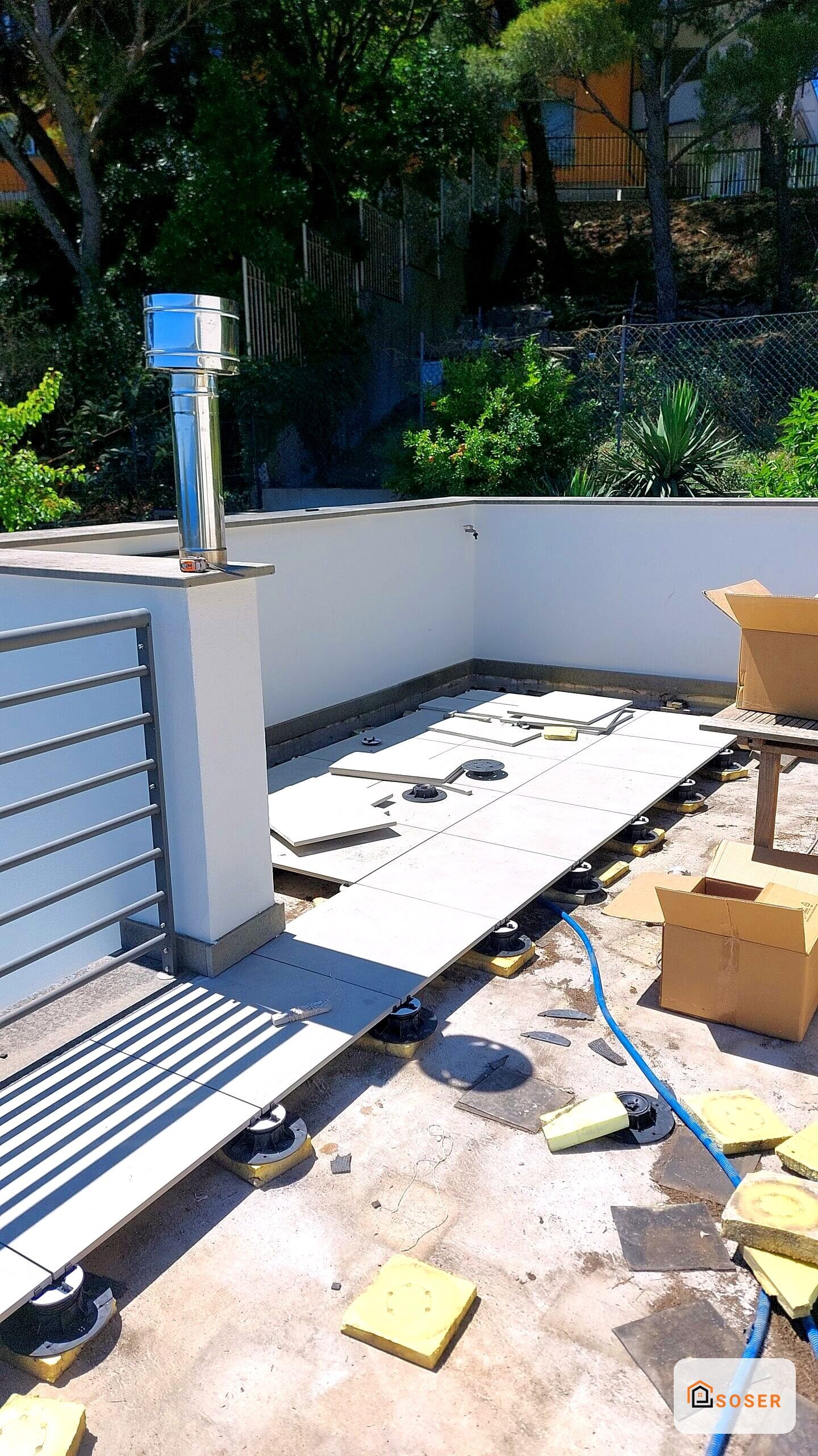 Terrazza in ristrutturazione con pavimentazione in piastrelle bianche su supporti regolabili e pareti in cartongesso