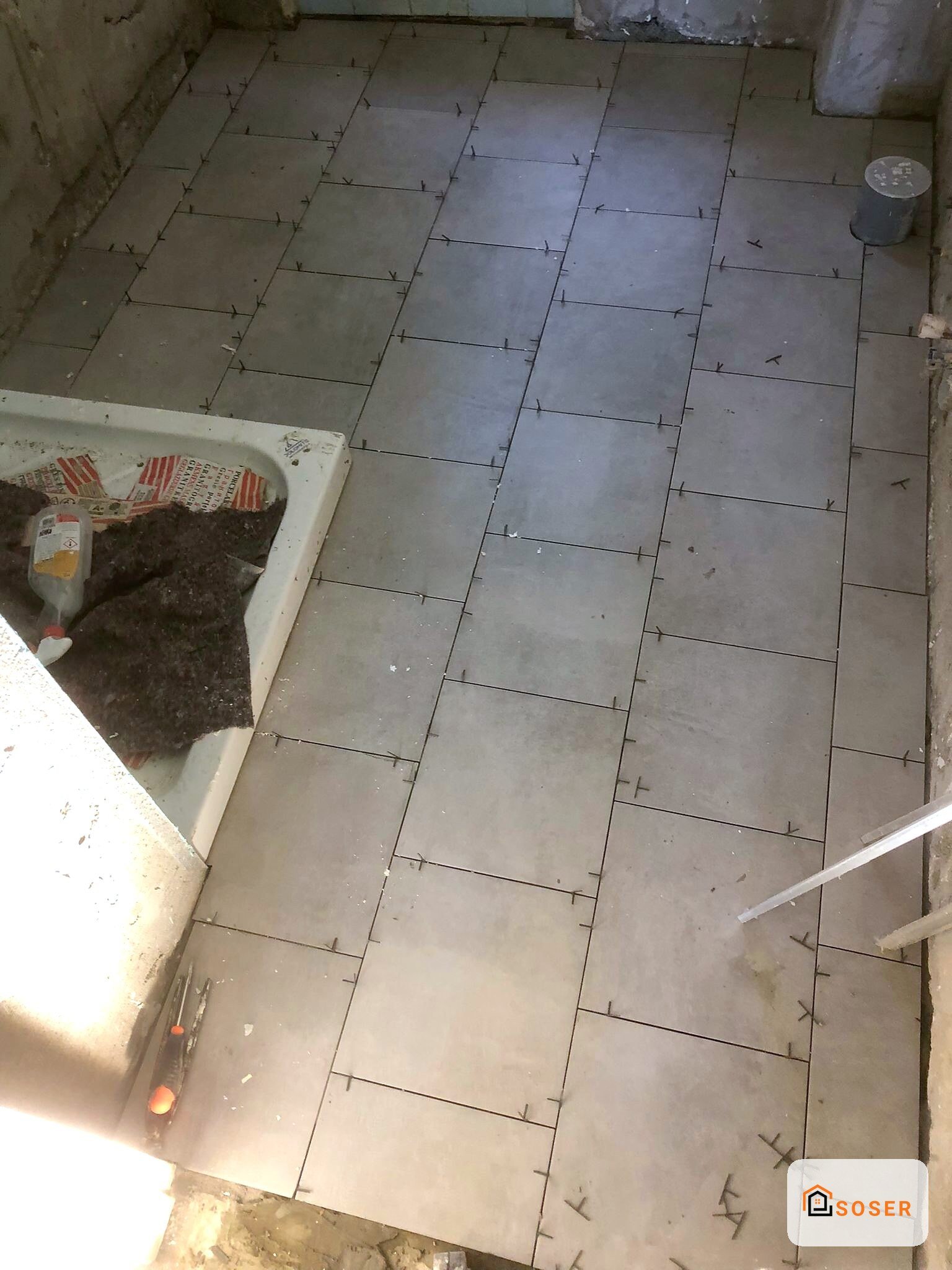 Posa pavimento in gres porcellanato con distanziatori, lavori in corso su sottofondo in cemento