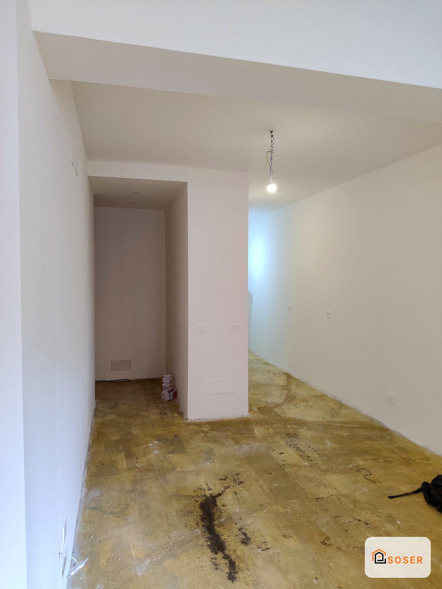 Interno in ristrutturazione con pareti in cartongesso bianco e pavimento in cemento grezzo