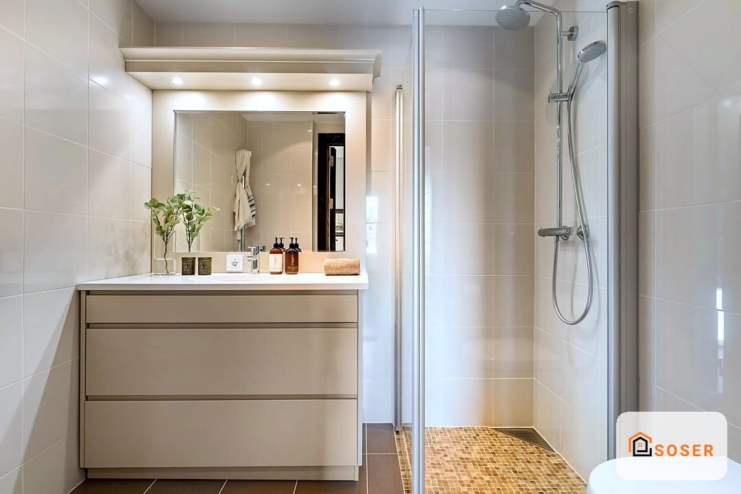 Bagno moderno con vanity beige, specchio illuminato e doccia con rivestimento in mosaico