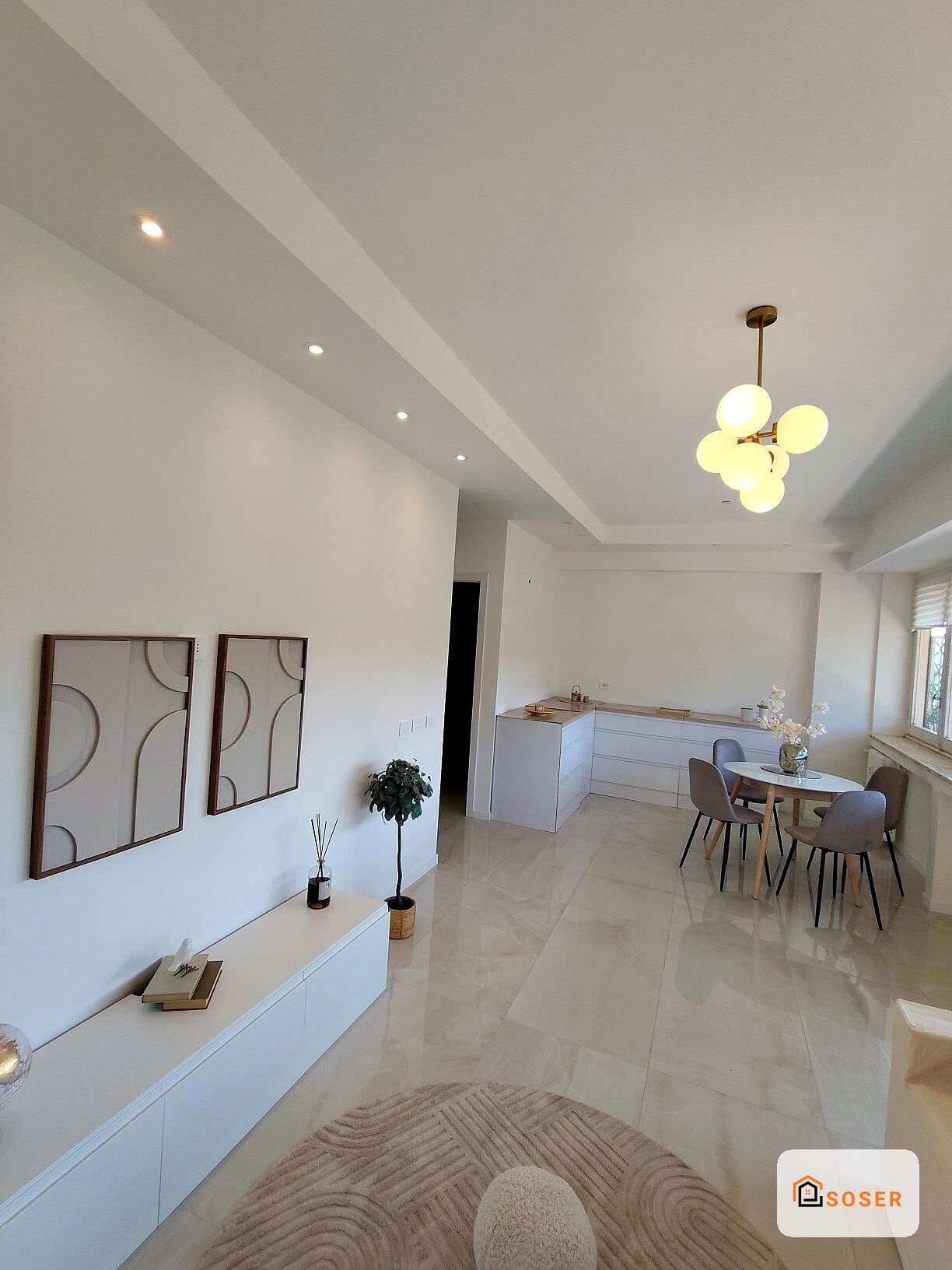 Soggiorno moderno con cucina open space, pavimenti in gres porcellanato, controsoffitto in cartongesso e lampadario design
