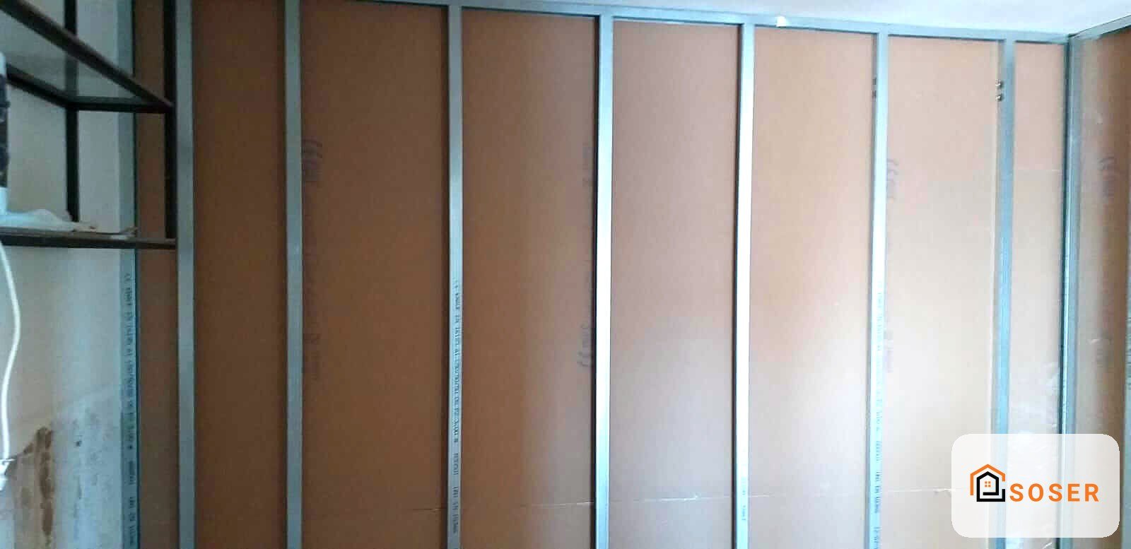 Parete in cartongesso con profili metallici e pannelli marrone in fase di realizzazione